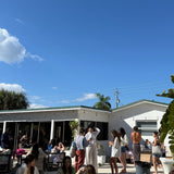 People relaxing on lounge chairs outside a building with a clear blue sky.