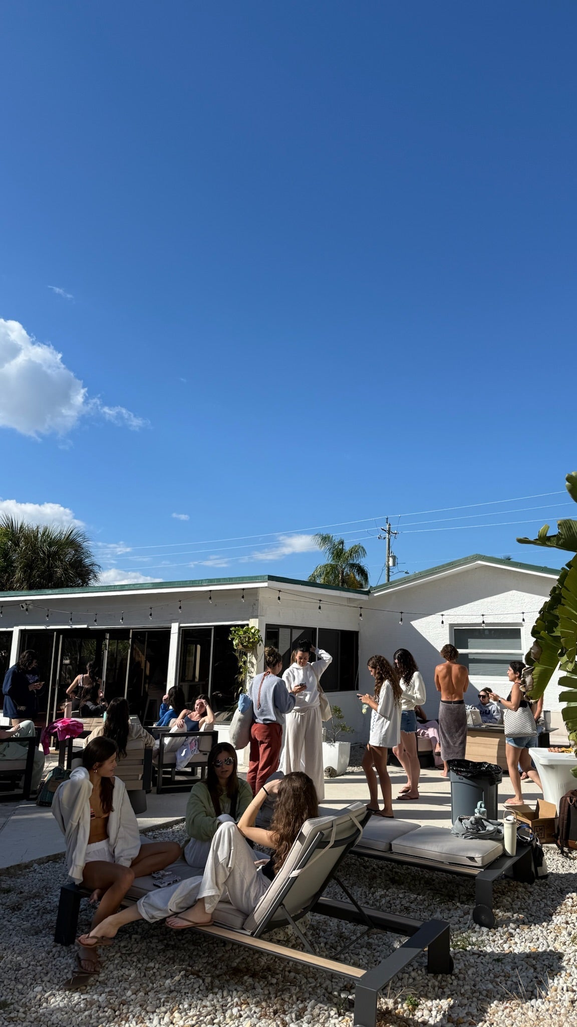People relaxing on lounge chairs outside a building with a clear blue sky.