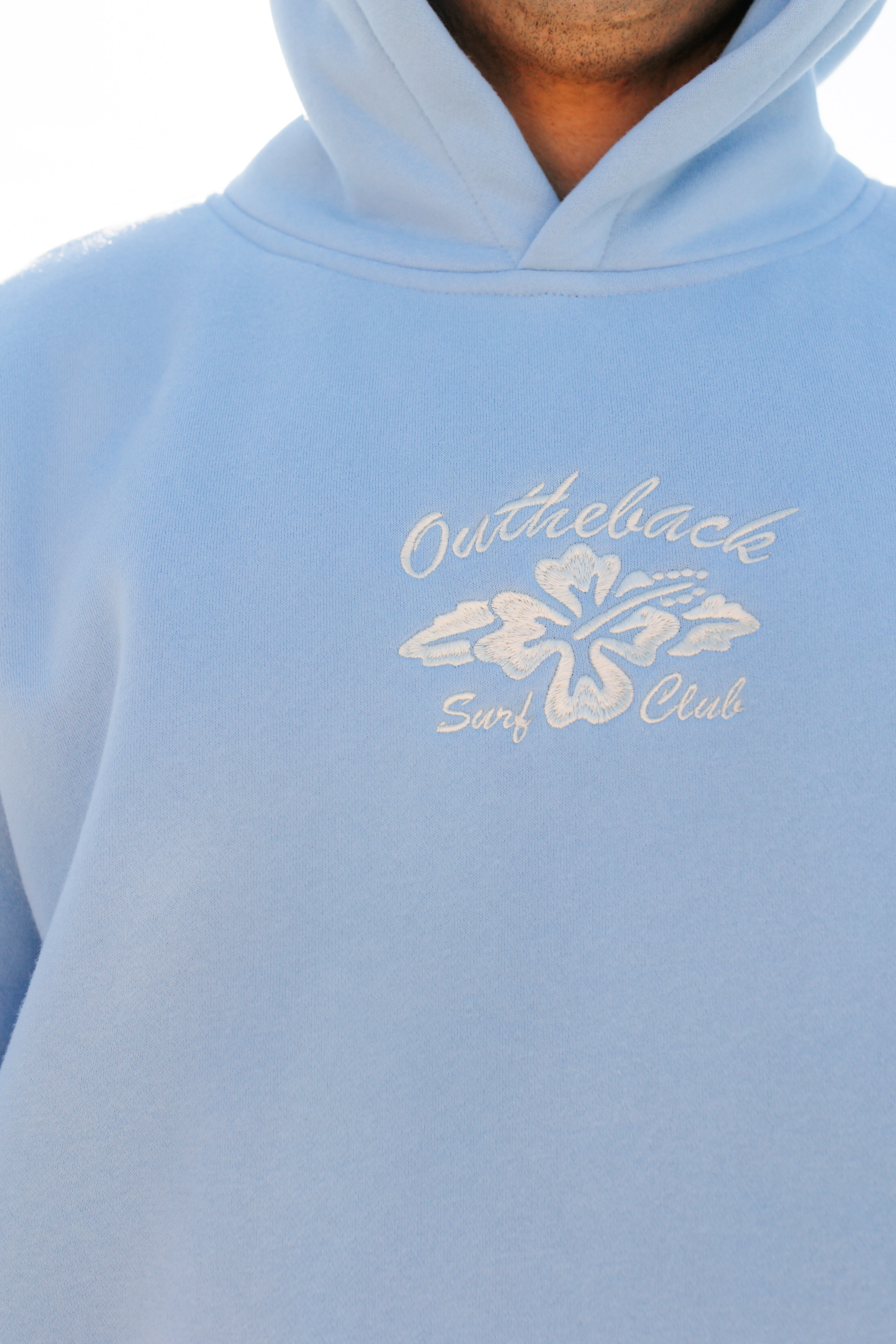 Light blue hoodie with 'Outtheback Surf Club' logo on a person wearing it.