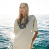 Woman wearing a white t-shirt with a logo on a boat with ocean in the background