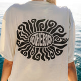 Person wearing a white t-shirt with a black graphic design by the water